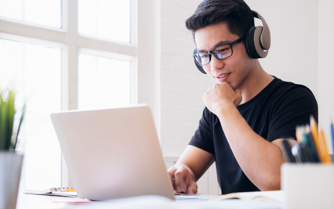 Gutt sitter foran Pc skjerm med headset på