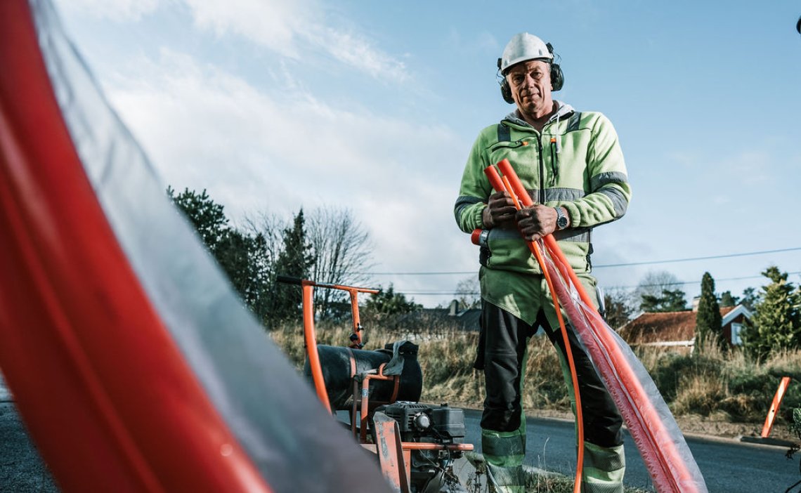 Mann viser fiberkabel i grøft