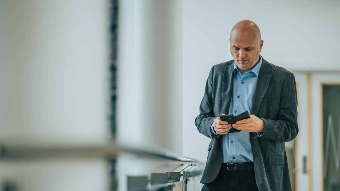 Sikkerheitsdirektør i Nkom, Svein Scheie, ser alvorleg på ein mobiltelefon.